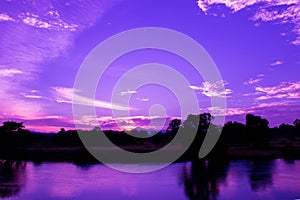 Dramatic sunset in sky and reflect river beautiful colorful tone blue- purple landscape silhouette tree woodland twilight time wit