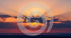 Dramatic sunset sky with sun rays breaking through clouds over ocean