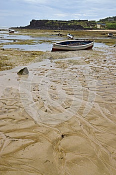 Dramatic Texture of Beach during Low Tide resembling random vein pattern with wooden boats and house in the background