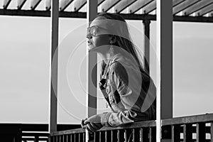 Dramatic thoughts concept. Profile portrait of young beautiful woman with long blond hair wearing stylish sunglasses, trendy jeans