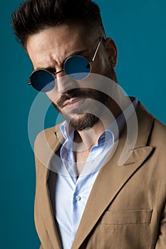 Dramatic unshaved man with retro glasses posing in a fashion manner