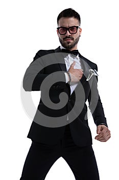 Dramatic unshaved man in tuxedo holding hands on chest