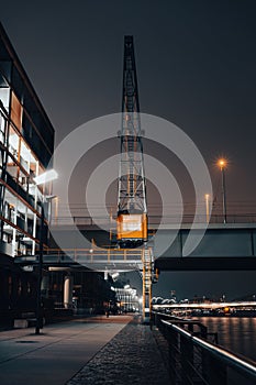 Dramatic vertical shot of a construction crane at the bridge at night