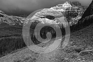 Dramatic view as the early morning sun breaks through the snow heavy clouds of Mt Babel at the back Consolation Lakes, Banff