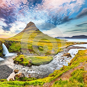 Dramatic view on Kirkjufellsfoss waterfall  near Kirkjufell mountain at sunset