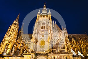 Dramatic view of the Prague Castle illuminated by warm yellow lights in a dark blue sky