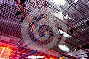 A dramatic view of the red corner of a regular boxing ring. Ropes in the corner of the ring.