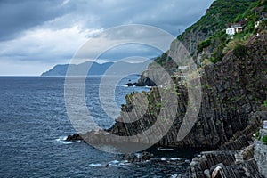 Dramatic view of a rocky coastline with jagged cliffs and an abundance of trees in  La Spezia, Italy