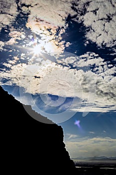 Dramatic view of silhouette mountainside against sundog sky