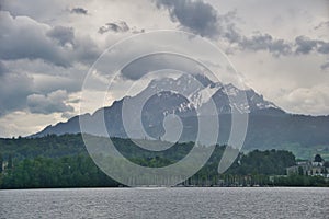 A dramatic view of snow capped alpine mountains and overcast sky over lake Lucerne in Luzern , Switzerland
