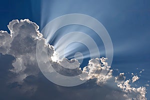 Dramatic Sun Rays Piercing Through Clouds in Blue Sky