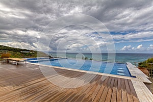 Dramatic view of Swimming Pool and Deck overlooking sea on a cloudy day in Pomos, Cyprus