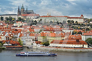 Dramatic view on Vltava river, tourist ship, Prague city center, Saints Vitus Cathedral and Prague Castle, Prague, Czech Republic