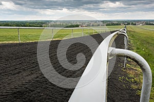 Dramatic, wide angle view of a racecourse barrier and track in the UK, seen from a hillside.