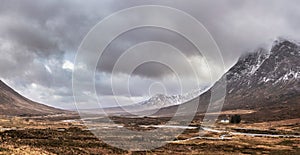 Dramatic Winter landscape image of white cottage at foot of Stob Dearg Buachaille Etive Mor peak in Scottish Highlands