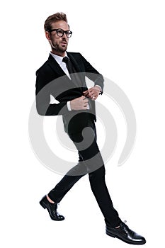 Dramatic young man in black suit buttoning jacket