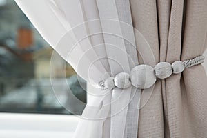 Draped window curtains with tieback in room