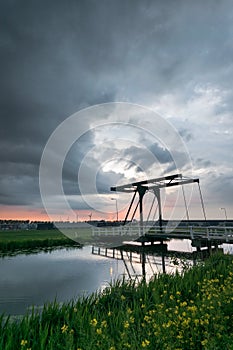 Draw bridge near a dutch canal close to the city of Gouda, Netherlands with a ominous storm cloud in the background