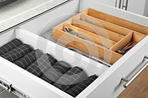 Drawer with different utensils and folded towels. Order in kitchen