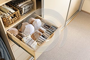 Drawer in the wardrobe with women's underwear, bras, briefs, socks and t-shirts. The concept of storage and order.