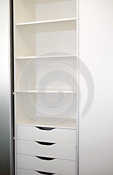 Drawers and shelves for storage in a wardrobe with mortise handles, modern wardrobe, furniture in the interior in white colors.