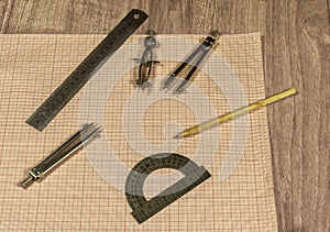 Drawing accessories and millimeter paper lie on a wooden surface