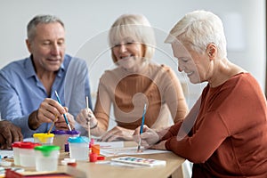 Positive elderly man and women enjoying painting with brush