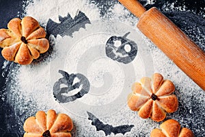 Drawing Halloween decorations on flour background, cakes in a shape of pumpkin and rolling pin. Halloween cooking concept