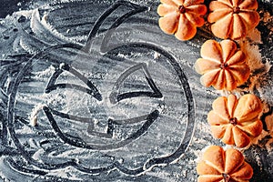 Drawing Halloween pumpkin on flour background and homemade cookies