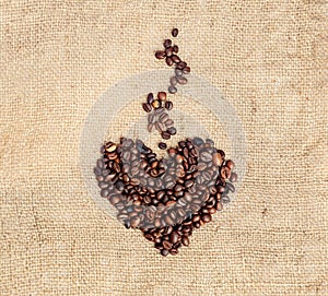 Drawing a heart with aromatic steam from coffee beans on a burlap. Vintage style.