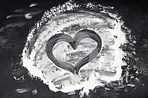 Drawing of heart on flour scattered over table, top view