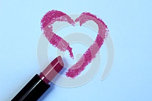 Drawing heart with lipstick on white paper, top view