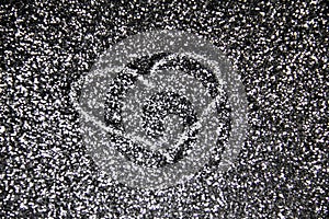 Drawing a heart on the silver sand glitter. A heart against a silver texture on the glitter background. A Shiny silver glitter on