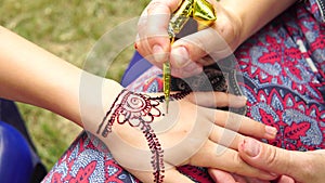 Drawing mehndi on the hand of a little girl closeup outdoors