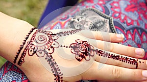 Drawing mehndi on the hand of a little girl closeup outdoors