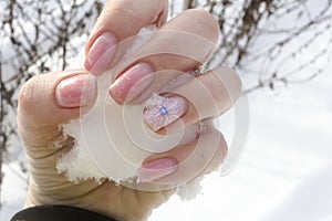 Drawing on the nails of snowflakes in manicure on a background of real snow