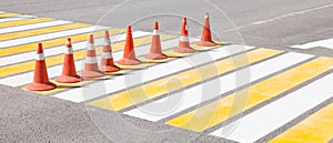 Drawing new white and yellow markings on the pedestrian crossing during road works with orange cones to indicate the bypass of