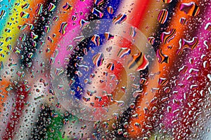 Drawing pencils reflected on waterdrops resting a piece of glass