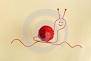 Drawing of red snail from wool threads with ball integrated knitting creative concept flat lay on