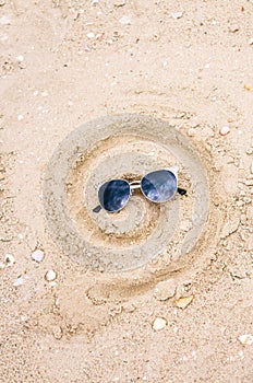 Drawing on sand, drawn smile in the form of a spiral, in sunglasses