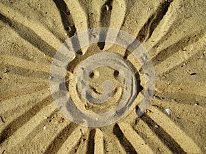 Drawing smiling sun on the sand