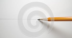 Drawing a straight line across paper with a yellow pencil