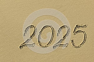 Drawing sun and 2025 on the sandy beach of the coastline as a symbol of the beach season