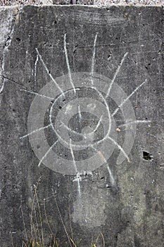 Drawing of a sun on a concrete vertical wall. Russian realities, color photo