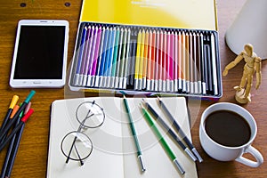 Drawing table, sketching pencils and sketchbook, empty paper and colorful pencils