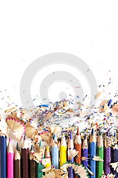 Drawing tools background. Lot of colorful pencils frame with sawdust and shavings on white