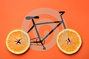 Drawn bicycle with orange slices instead of wheels on coral background, top view