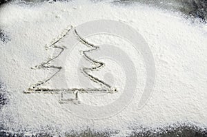 Drawn Christmas tree on flour scattered. Silhouette of Christmas tree made of flour, dark background