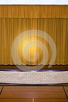 Drawn curtains with spotlight on school stage