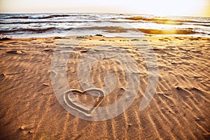 Drawn heart shape on sea sand beach.